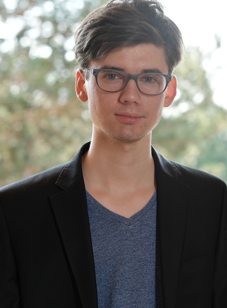 Psychotherapeut Raphael Höfinger steht in einem Park im Grünen in 1030 Wien